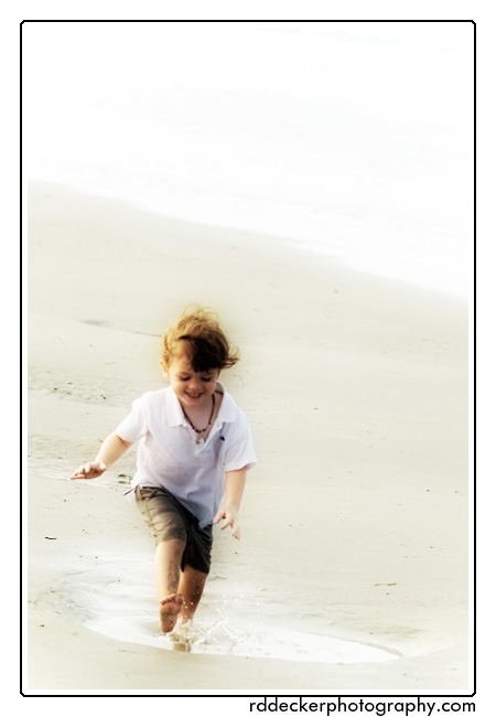A young boy splashes in a puddle on the beach at Fort Macon State Park, Atlantic Beach, North Carolina.  What a lovely vacation memory from a Bogue Banks visit.